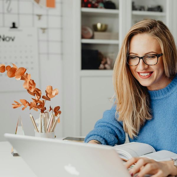 Smiling woman working on her laptop in a cozy home environment.